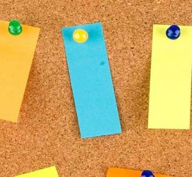 Foto Pinnwand aus Kork mit angehefteten bunten Zetteln.